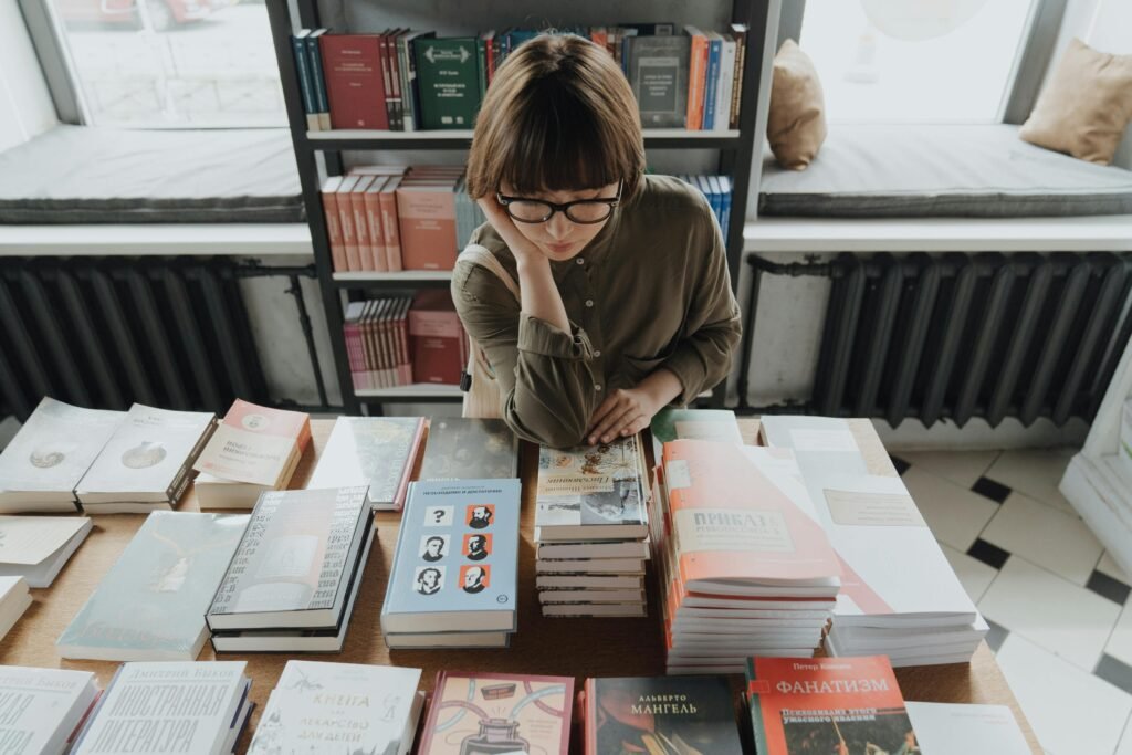 A young woman with glasses browsing books in a cozy bookstore.